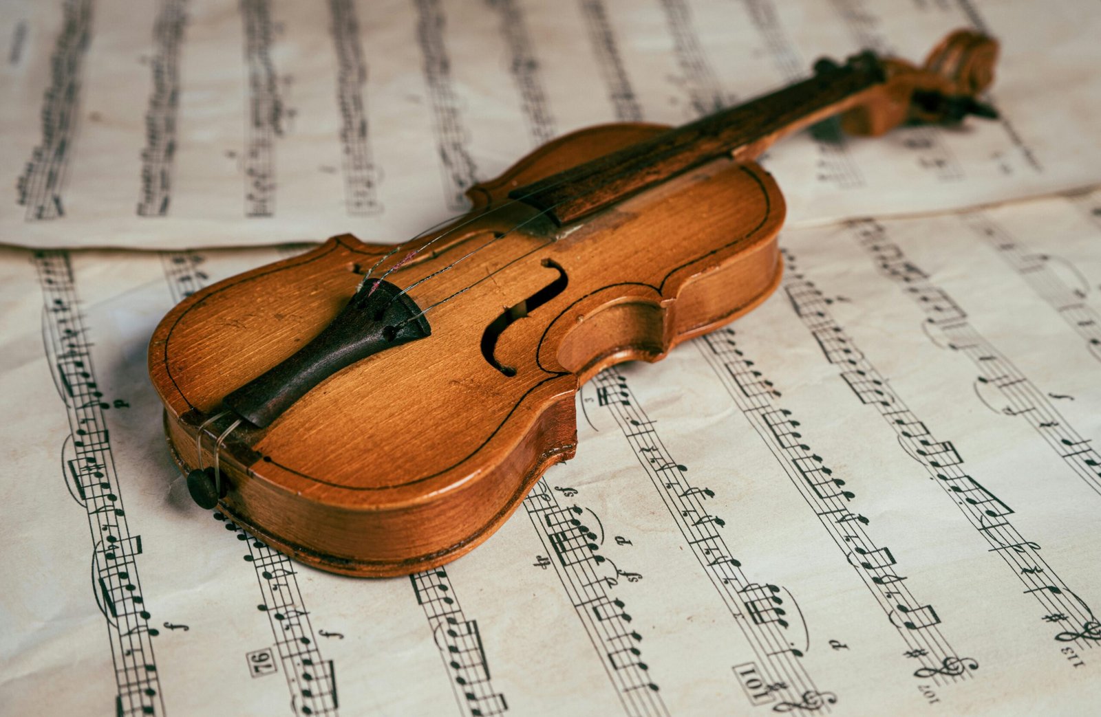 Close-up of a vintage violin resting on sheet music, highlighting the beauty of classical music.